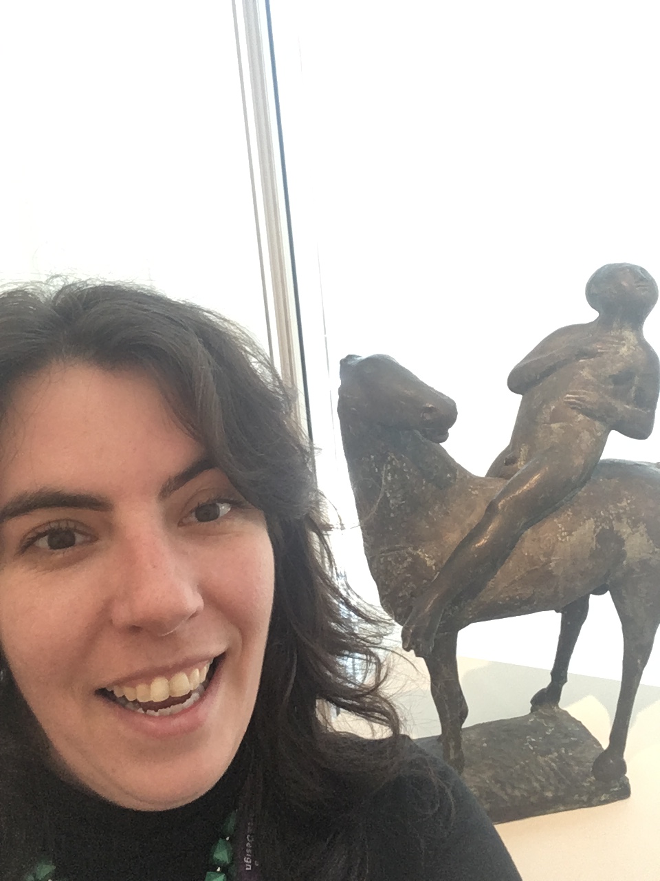 Selfie of woman smilling and bottom left with sculpture by Marino Marini (bronze "horse and rider") at center right